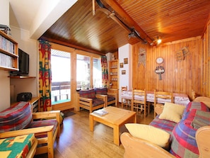 A cozy wooden interior with a sofa, chairs, a table, and a television.