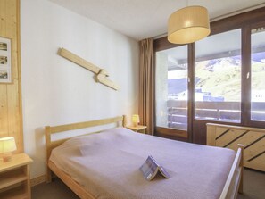 A bedroom with a wooden bed, a bedside table with a lamp, a window with a view of a mountain, and a wooden wall decoration. - Beautiful apartment for 6 guests with WIFI, TV and balcony (Les Boisses)