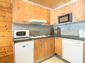 A kitchen with wooden cabinets, a microwave, a stove, and a dishwasher. - Beautiful apartment for 6 guests with WIFI, TV and balcony (Les Boisses)