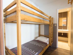 A bunk bed room with a wooden frame, a single bed with a patterned blanket, and a small window. - Lovely apartment for 6 people with WIFI, TV and balcony (Les Boisses)