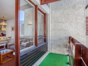 A narrow balcony with a green artificial turf floor, a wooden railing, and a view of a building with a textured wall. - Lovely apartment for 6 people with WIFI, TV, balcony and panoramic view (Les Boisses)