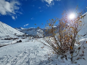 A snowy landscape with a clear sky, a mountain in the background, and a small building with a snow-covered roof.