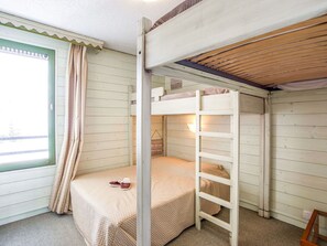 A bunk bed room with a window, curtains, and a ladder.