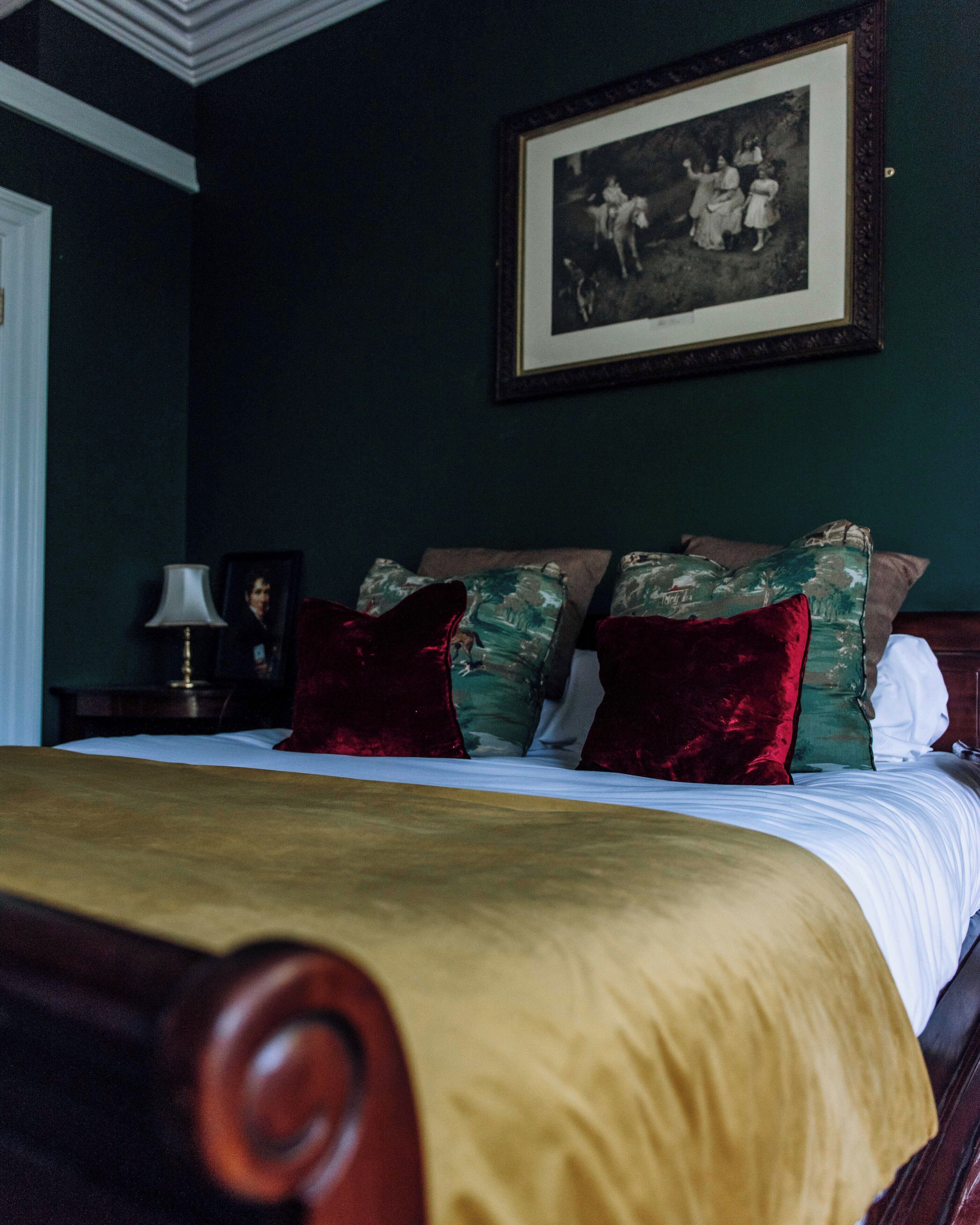 Une chambre à coucher avec un lit, des oreillers, une table de chevet, une lampe et un tableau encadré au mur.