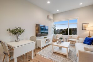 Relax in this stylish living room with a dining table, sofa, and armchair, plus a large window offering a view of the outside.