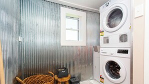 Une buanderie équipée d’un lave-linge, d’une fenêtre et d’un panier en osier.