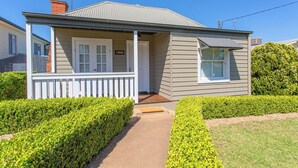 Une maison de plain-pied avec un porche à l’avant, un petit garage attenant et une pelouse bien entretenue.