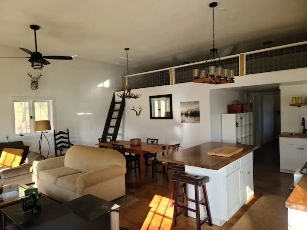 A spacious living area with a sofa, dining table, and kitchen island.