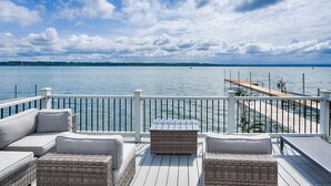 A deck with wicker furniture and a view of the water. - Petit Retreat: The sweetest place on the Lake! (Seneca Falls)