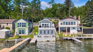 A waterfront property with a dock, a house with a balcony, and a house with a covered porch. - Petit Retreat: The sweetest place on the Lake! (Seneca Falls)