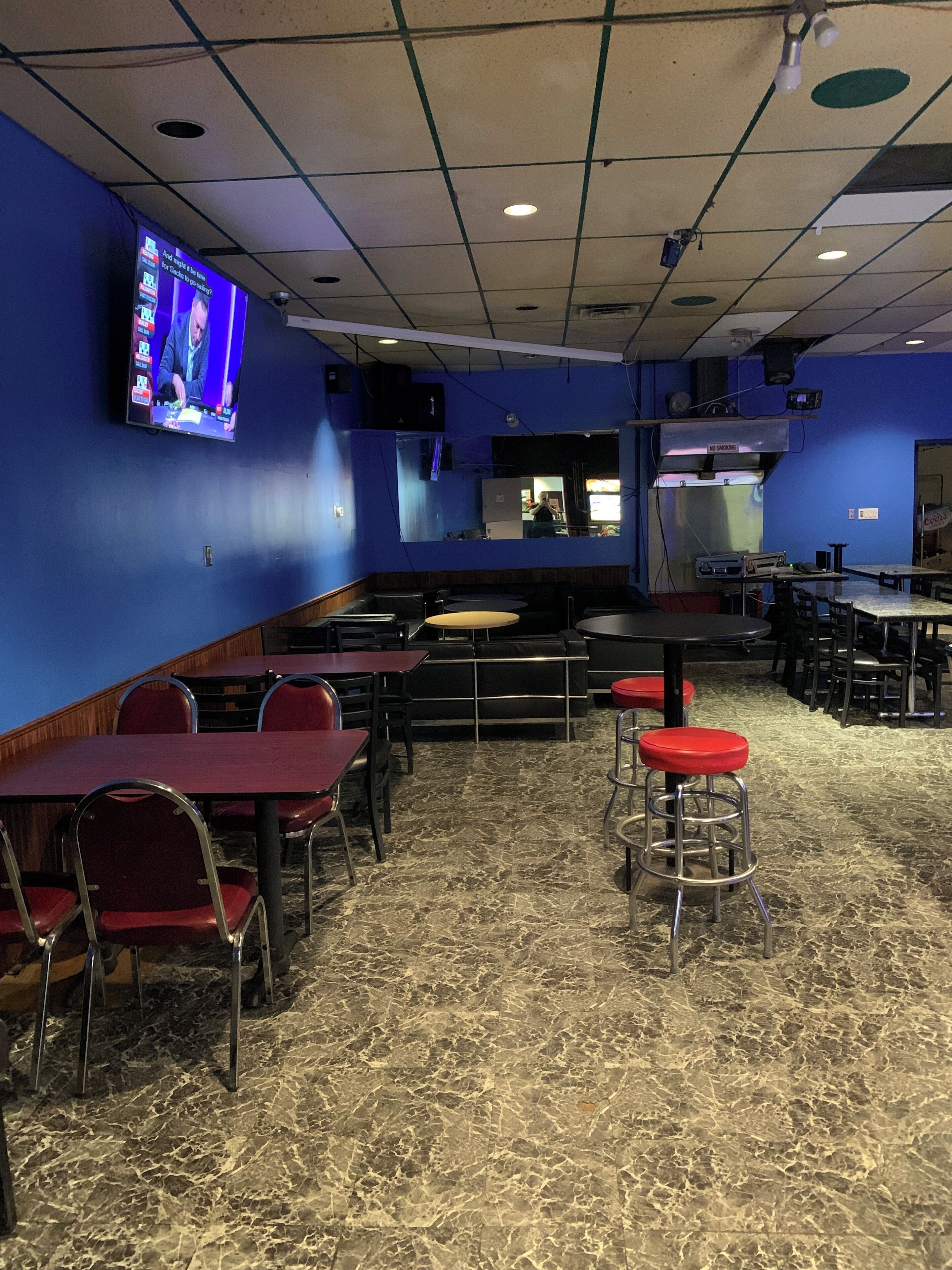 A restaurant with booths, high-top tables, and red bar stools.