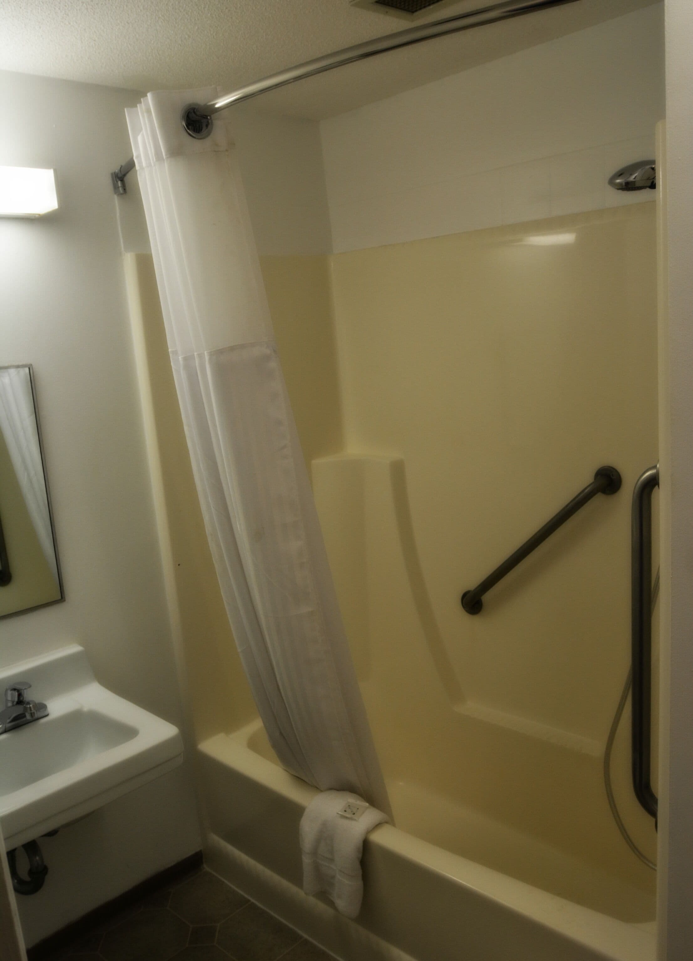 Un baño con ducha, lavamanos y espejo.