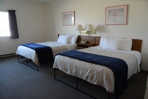 A hotel room with two single beds, a bedside table with a lamp, and a window with curtains.