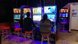 A bar area with multiple arcade machines and stools. - Whitewood Inn (Whitewood)