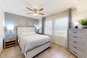 Relax in this serene bedroom with a large bed, nightstand, and dresser, plus a ceiling fan for comfort.
