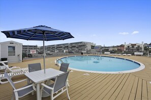 Relax by the oval-shaped pool surrounded by lounge chairs and a shaded table.
