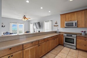 A kitchen with wooden cabinets, a microwave, an oven, and a ceiling fan.