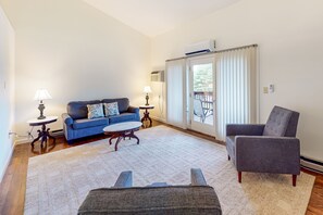 Relax in this stylish living room with a blue sofa, armchair, and coffee table, offering a view of the outdoors.