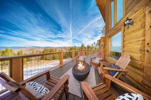 Un terrazzo in legno con un braciere e sedie, affacciato su un paesaggio suggestivo.