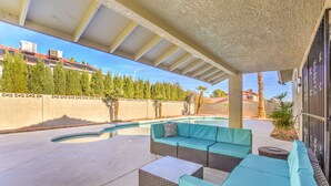 A covered outdoor area with a swimming pool, wicker furniture, and a view of a residential neighborhood. - The  Oasis (Las Vegas)