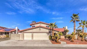 A two-story house with a red-tiled roof, a garage, and a driveway. - The  Oasis (Las Vegas)