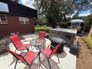 Une terrasse avec des chaises rouges, une table ronde et un barbecue extérieur.