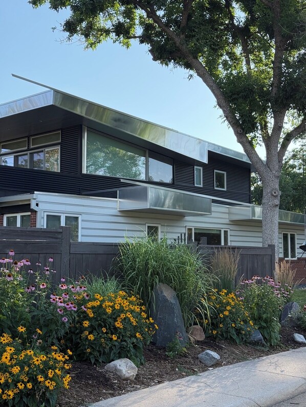 Une maison moderne à deux étages, dotée d’une grande fenêtre et d’un balcon.