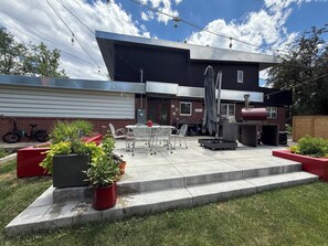 Une terrasse moderne, aménagée avec du mobilier d’extérieur, un barbecue et des plantes en pot.