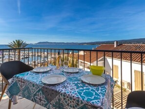 Ein Balkon mit einem Tisch für zwei Personen, mit Blick auf einen Hafen und das Meer.