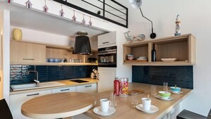 A modern kitchen with a wooden island, white cabinets, and a blue backsplash. - La Corniche by Interhome (Saint Cyr sur Mer La Madrague)