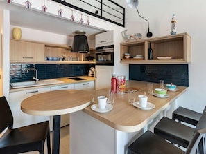 Cozinha moderna com ilha de madeira, armários brancos e painel atrás do fogão azul.