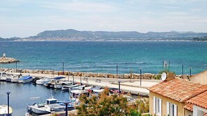 A coastal marina with boats docked, a stone breakwater, and a building with a tiled roof. - La Corniche by Interhome (Saint Cyr sur Mer La Madrague)