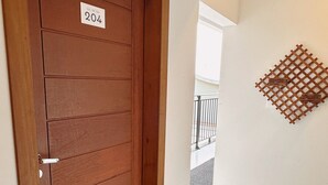 A wooden door with a number plate, a tiled floor, and a wall-mounted decorative lattice. - Pousada Villa Vantino (Penha)