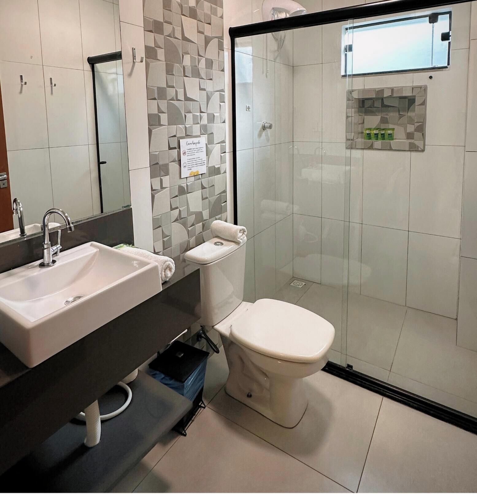 Une salle de bain moderne avec un lavabo blanc, des toilettes et une douche à parois de verre.