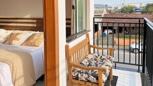 A balcony with a wooden bench and a bed with patterned pillows. - Pousada Villa Vantino (Penha)