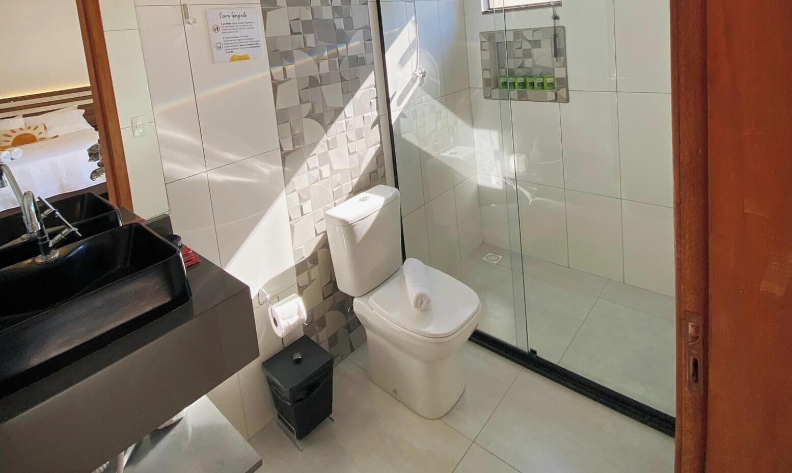 A modern bathroom with a toilet, sink, and glass shower enclosure.