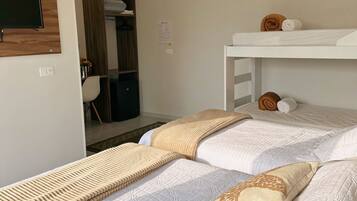 Habitación de hotel con dos camas, un armario, un escritorio y un equipo de aire acondicionado.
