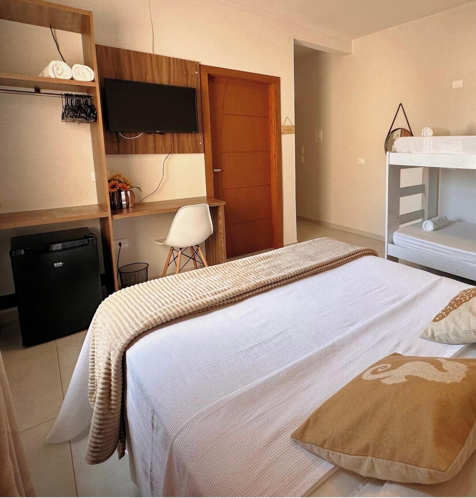 A bedroom with a bed, a desk, a chair, a TV, and a wardrobe.