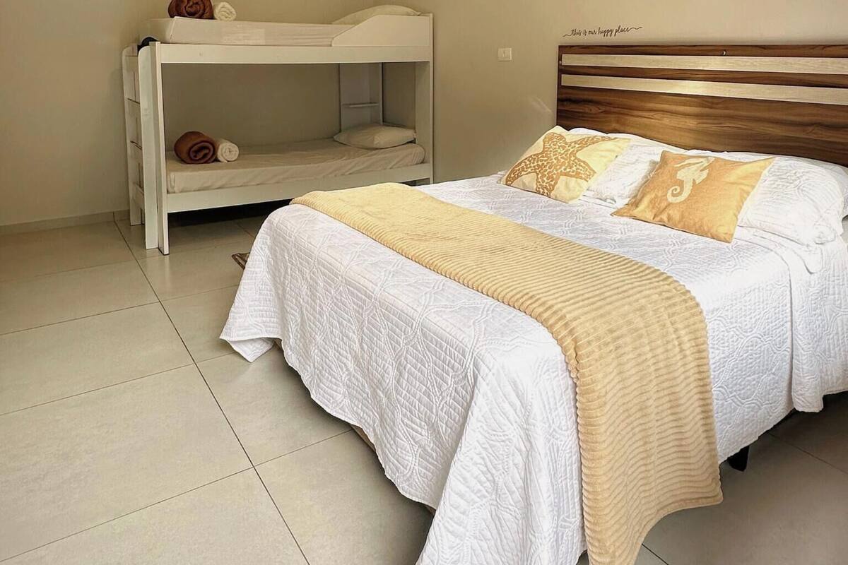 A bedroom with a bunk bed and a single bed, both with white bedding and decorative pillows.
