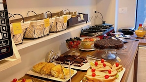 A buffet with various food items including bread, pastries, and desserts. - Pousada Villa Vantino (Penha)