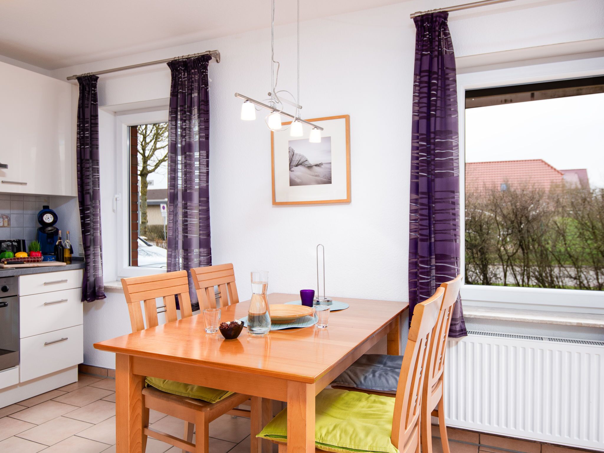 Een moderne keuken met een eettafel, stoelen en uitzicht op buiten.