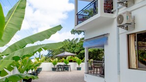 A two-story building with a balcony, outdoor seating, and air conditioning units. - 2-Bed Apt, Sleeps 4, near Beau Vallon Beach (Mahe)