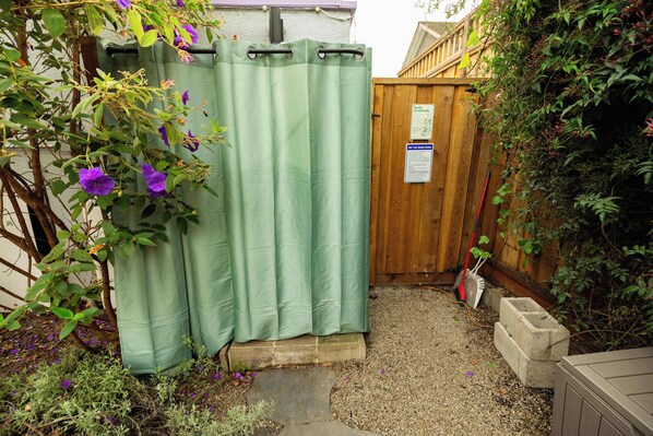 A garden with a green curtain, a wooden fence, and a concrete block.