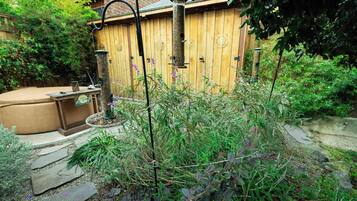 Un jardin avec une clôture en bois, une mangeoire à oiseaux et un jacuzzi.