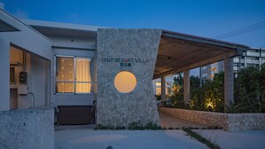 Ein modernes Gebäude mit einer Steinfassade und einem Rundfenster. Auf der Fassade ist der Name "Sent Resort Villa" sichtbar.