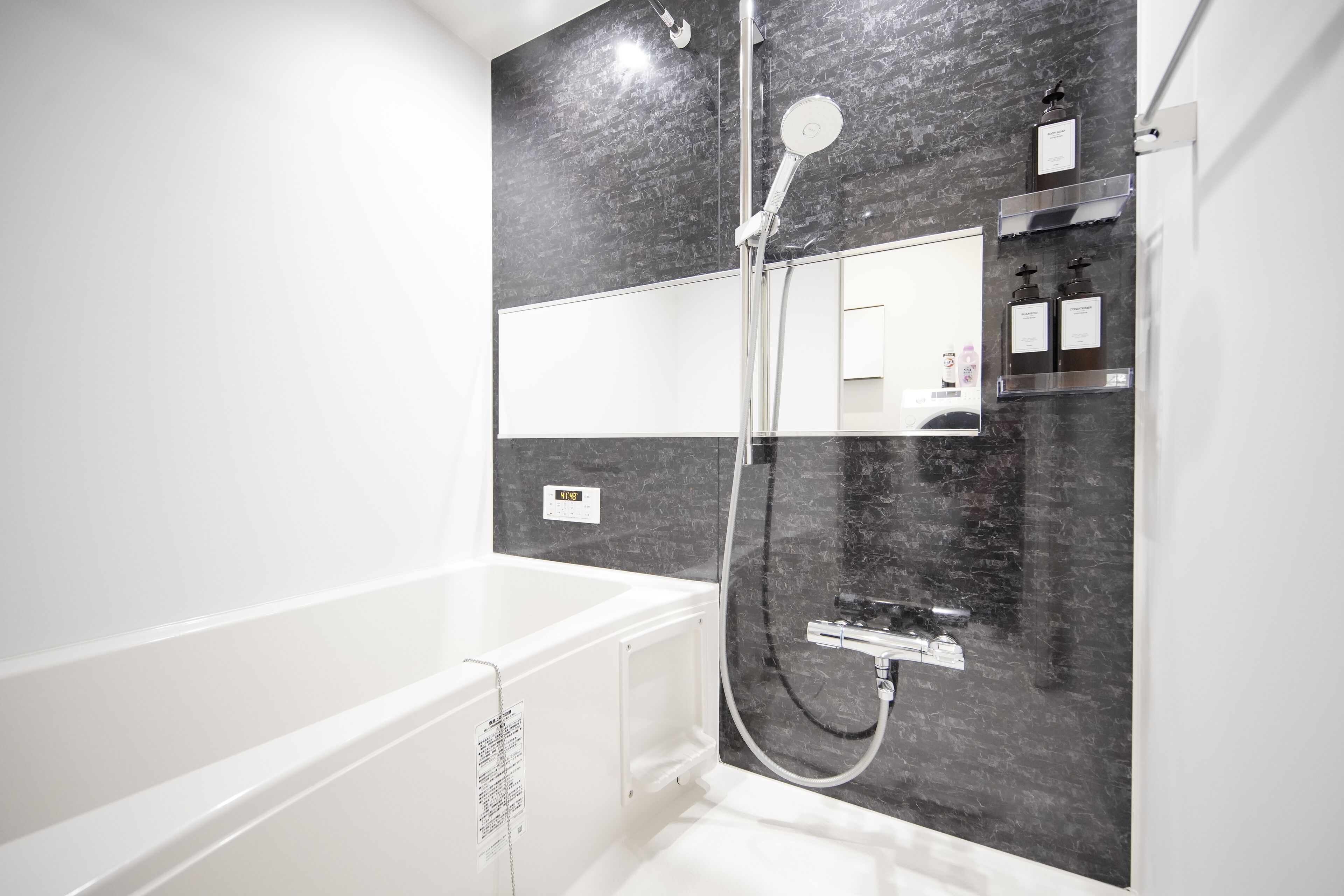 A modern bathroom with a white bathtub, a glass-enclosed shower, and a marble backsplash.