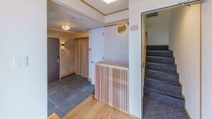 A modern interior with a staircase, a radiator, and a ceiling light fixture. - Yadoya Suzume (Tokyo)
