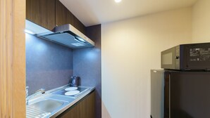 A compact kitchen with a built-in microwave, a sink, and a stainless steel refrigerator. - Yadoya Suzume (Tokyo)