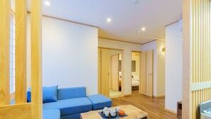 A modern living room with a blue sofa, wooden coffee table with tea set, and a wooden floor. - Yadoya Suzume (Tokyo)