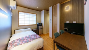 A hotel room with a bed, a desk with a computer, a TV, and a window with blinds. - Yadoya Suzume (Tokyo)